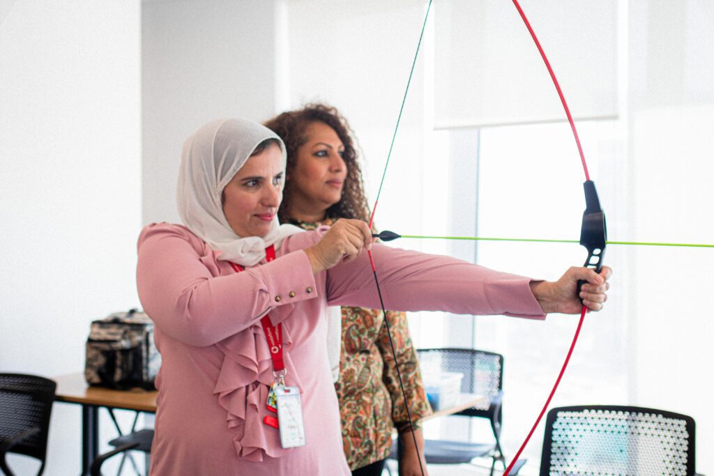 Woman participating in a team-building activity with a bow and arrow