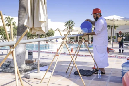 Qatari man participating in a team-building activity, constructing a water pipeline