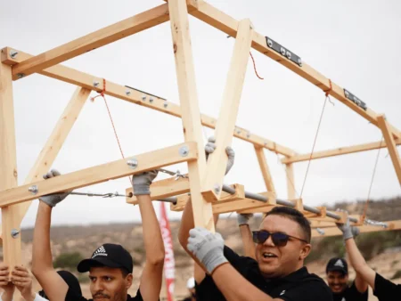 4 men smiling and holding a bridge in a team building activity